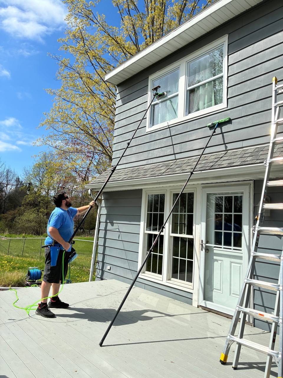 Water fed pole cleaning two upper-story windows with no ladder touching the house